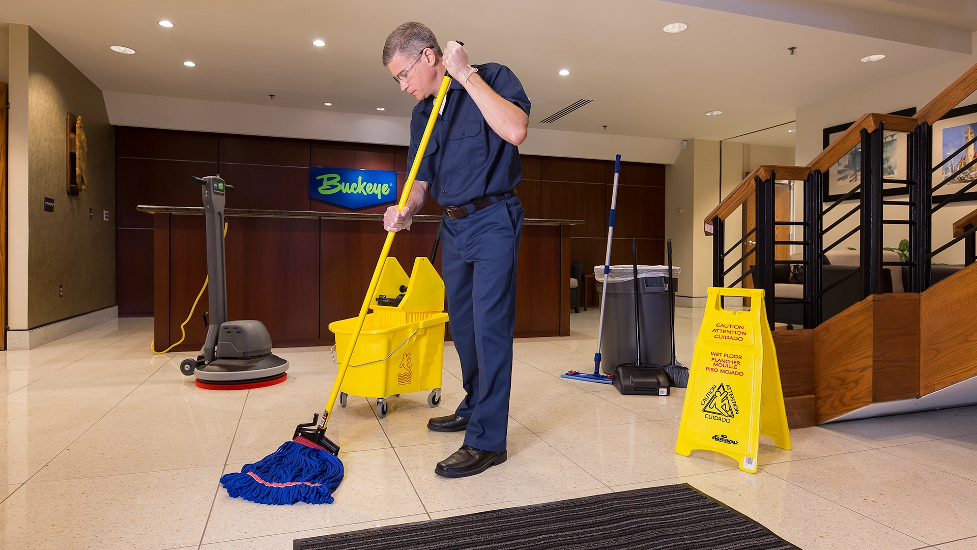 Custodian using a mop in an office lobby